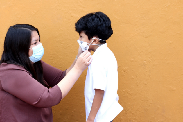 Woman adjusting child's mask.