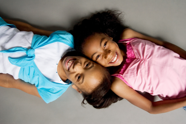 Photo of sisters lying on the ground together, smiling.