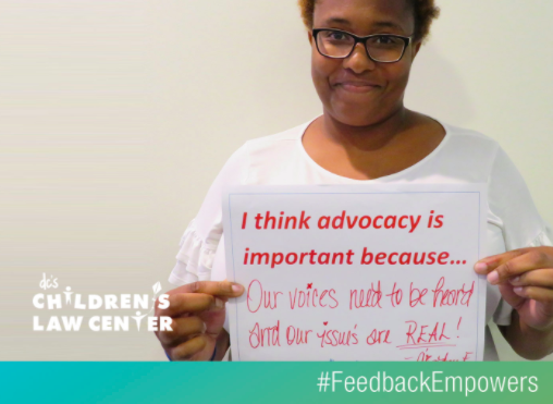 Advocate holding sign to promote the #FeedbackEmpowers campaign.