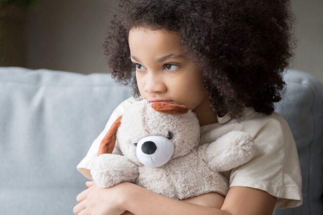 Stock photo of young girl hugging teddy bear.