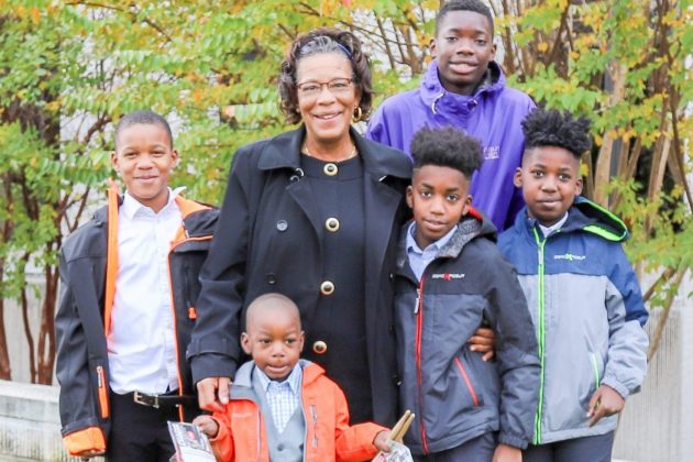 A woman and five boys post for a picture outside with their arms around each other