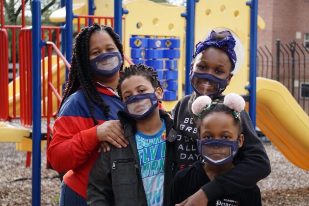 Family with masks at playground.